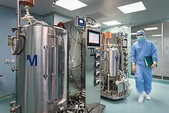 Mitarbeiter in Schutzkleidung in einem biotechnologischen Labor mit Edelstahlbehältern und Anlagen